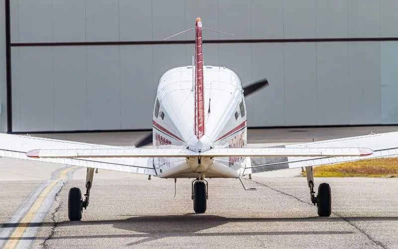Piper Archer TX seen from behind on the ramp outside a hangar
