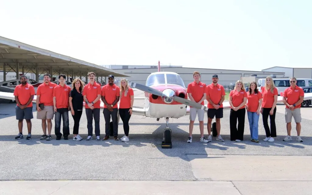 Thrust Flight team standing on the ramp in front of a training aircraft